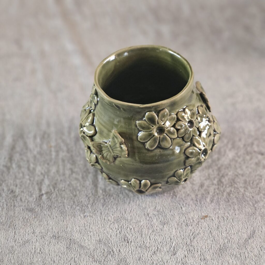 Vas grön med blommor och fjärilar.